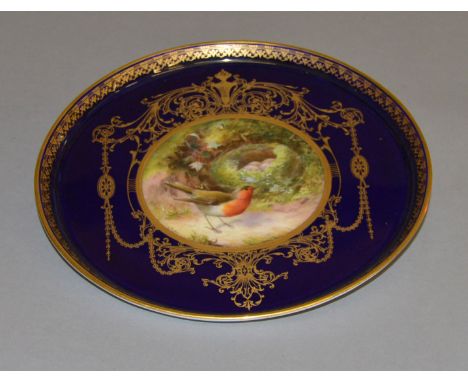 A Royal Worcester gilded plate with raised edges. Central painting signed "L. Flexman". 25cm diameter.
