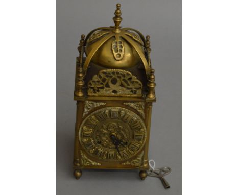 A brass lantern clock with heavy relief design to face. 36cm tall.