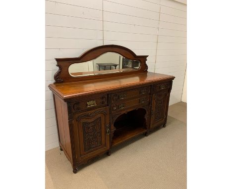 An ornate sideboard with carved panel doors and brass drop handles 