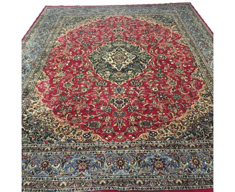 KASHAN CARPET, 380cm x 300cm, central medallion on a ruby field of palmettes and scrolling vines within corresponding bands a