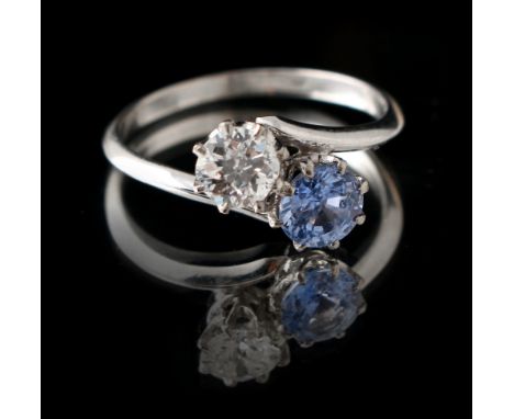 A platinum sapphire &amp; diamond two stone crossover ring, the clear cornflower blue sapphire probably Ceylon, the round bri