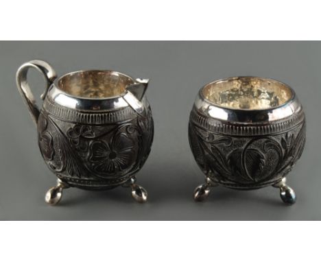 Property of a deceased estate - a carved coconut &amp; white metal mounted cream jug and matching sugar basin, the white meta