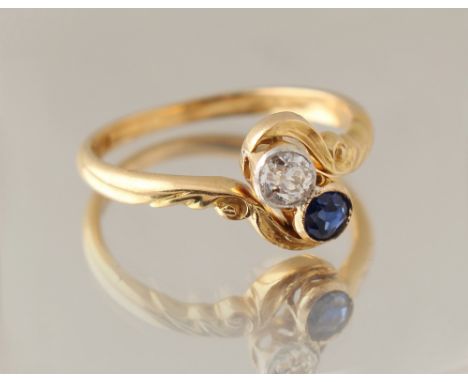 An early 20th century 18ct yellow gold sapphire &amp; diamond two stone crossover ring, the stones in rub-over collet setting