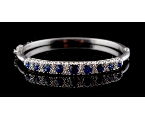 A late Victorian sapphire &amp; diamond hinged bangle, set with nine graduated oval cut sapphires alternating with pairs of r