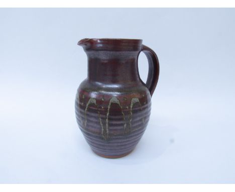 A Winchcombe Pottery jug with iron red glaze and waved line detail. Impressed pottery seal 20.5cm high   