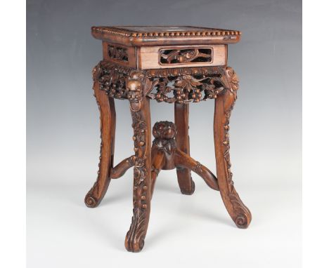 A Chinese hardwood jardinière stand, late 19th century, the square top inset with a rouge marble panel, the legs carved with 