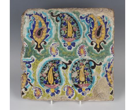 A Persian tin glazed earthenware tile, decorated with polychrome foliate-filled boteh, 24.5cm x 24.5cm (repaired corner, some