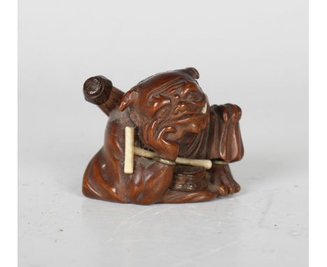 A Japanese carved wood netsuke, Meiji period, finely modelled as a seated oni with parasol slung over his shoulder and an ivo