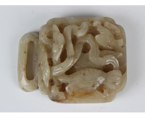 A Chinese pale celadon jade buckle, probably late Qing dynasty or later, the shaped square panel carved in relief with a cran