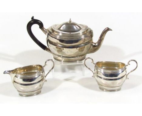 A George V silver three piece tea service, comprising cape shaped teapot, with ebonised thumb scroll handle, 15cm high, milk 