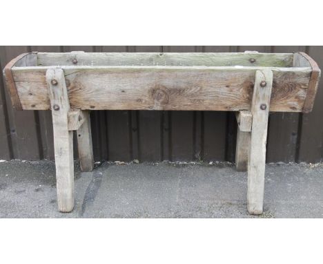 A 19thC trough, with part metal banding on shaped inverted supports with heavy bolt fastenings, 76cm high, 150cm wide, 54cm d