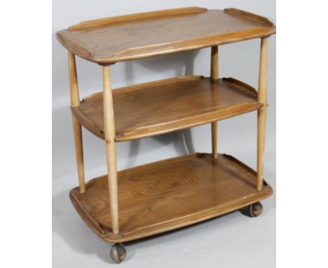 A 1960's Ercol light elm three tier trolley, the rounded sections broken by cylindrical supports raised on castors, 79cm high