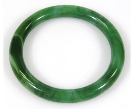 A 20thC Chinese jade bangle, of polished plain outline, with flecks of colour predominantly in dark and light green, 8cm diam