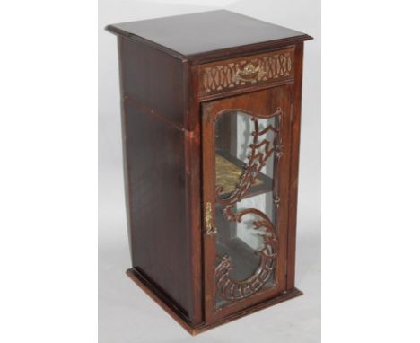 An early 20thC mahogany cabinet, with blind fret drawer above a glazed 'S' scroll panel door, hinging to reveal a shelved int