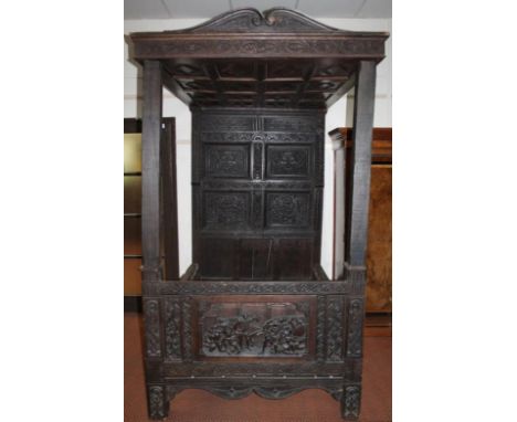 A Jacobean style oak single four poster bed, with a heavily carved diamond canopy top raised above plain square supports with