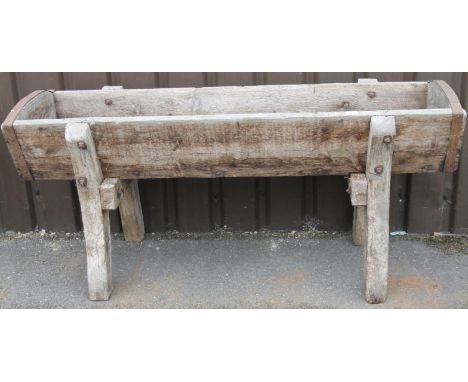A 19thC trough, with part metal banding on shaped inverted supports with heavy bolt fastenings, 71cm high, 150cm wide, 57cm d