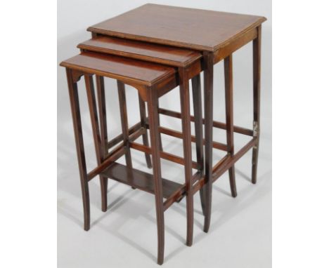 An Edwardian mahogany nest of three tables, each with rectangular outline with a wide walnut crossbanding, with square sabre 