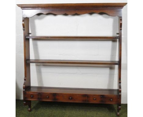 A George III style oak hanging shelf, the overhanging moulded top raised above three delft racks and five various spice drawe