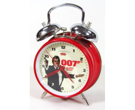 An EON Zeon James Bond 007 alarm clock, with elaborate bell top red outline on shaped supports, with Roger Moore back plate, 