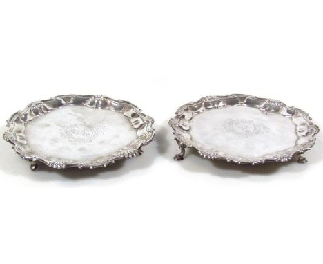 A near matching pair of George II silver waiters, each probably by Hugh Mills  of piecrust outline on triple hoof supports, c