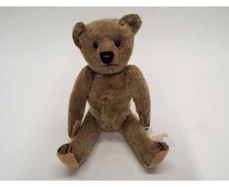 An early 20th century Steiff style teddy bear with "FF" button to its ear,  short pile mohair covered body with original boot