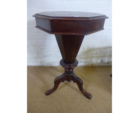 A Victorian walnut sewing table - the hinged octagonal top enclosing a fitted above tapering sides, standing on carved tripod