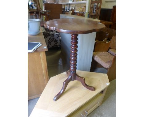 A walnut tilt top wine table with shaped top raised on turned pedestal terminating in tripod base 