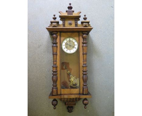 A Vienna wall clock with Roman numerals to white enamel chapter ring, pendulum behind glass door