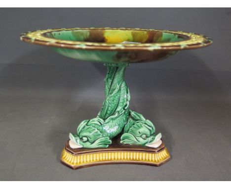 A Wedgewood Majolica Tazza with pierced outer ring decorated with brown, yellow and green glaze raised on a dolphin tripartit