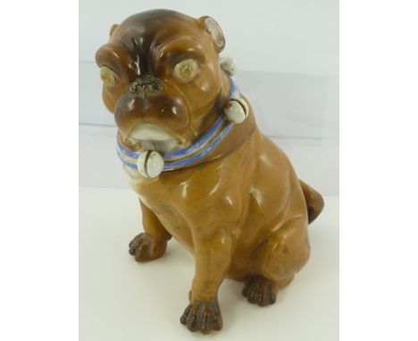 A GERMAN CERAMIC PUG DOG, with removable head, seated wearing a blue collar mounted with bells, circa 1900, considered to rep