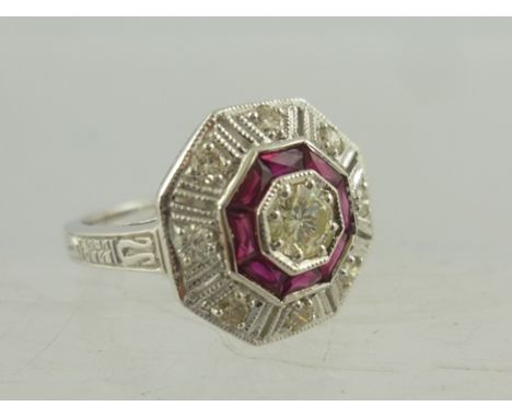 A RHODIUM FINISHED 18CT WHITE GOLD RUBY AND DIAMOND CLUSTER RING, having octagonal Deco style head on tooled shoulders and pl