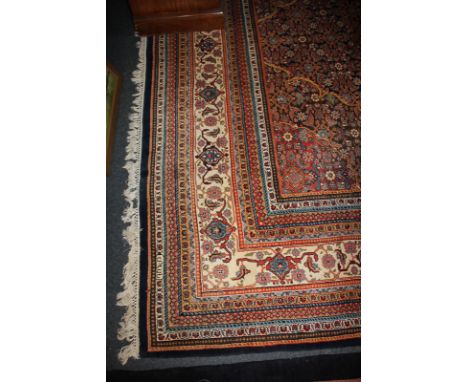 A large Persian style carpet with all-over floral decoration and central motif within multiguard borders, on dark blue ground