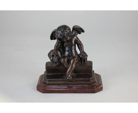 A late 19th century bronzed vanitas figure of a cherub seated on a step beside a skull and an hourglass, marked VM164, on red