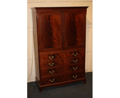 A George III style mahogany cocktail cabinet with flame veneered cupboards enclosing cut-out shelf above mirrored glass slide