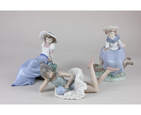 A Nao figure of a ballerina lying with a ball, 25cm long, and two others of women with birds
