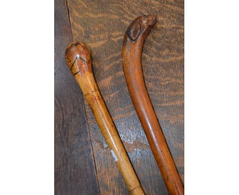 A 19th century novelty walking cane, the pommel carved as the head of a dog; another, painted as a comical man, wearing a bow