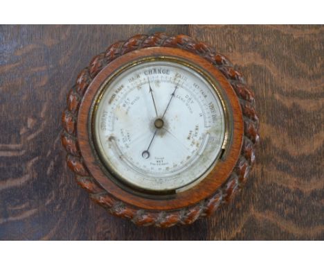 An Edwardian carved oak rope twist wall hanging barometer, white dial and thermometer scale c.1910