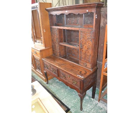 A 19th century oak dresser, outswept cornice, shaped apron, long shelf over short shelf flanked by cupboards and drawers to t