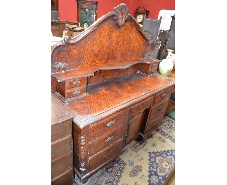 A Victorian scumbled pine sideboard, cresting gallery carved with swags, shaped shelf over recess flanked by two pairs of dra