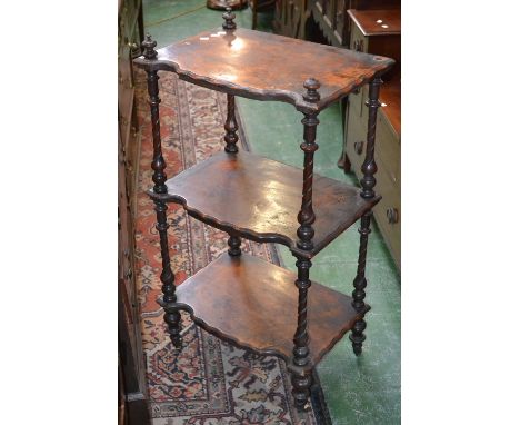 An early 19th century walnut three tier what not, each tier with moulded serpentine edges, knop finials, spirally fluted upri