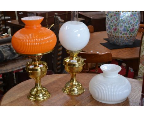 A brass effect oil lamp, ridged orange and white glass shades and chimney;  another with globular shade (3)