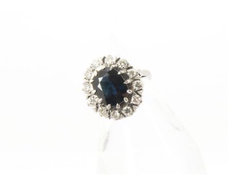 A 1960s white 18ct gold sapphire and diamond cluster dress ring, oval central blue stone, slightly loose, surrounded by brill