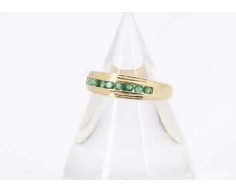 A modern 14ct gold and emerald ring, having nine channel set round cut green stones, 2.3g and size M 