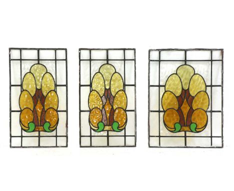 Three Art Deco stained glass panels,1920s, each centred with 'cloud' panels, in amber, green and amethyst, comprising a pair 