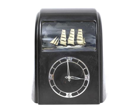 An Art Deco Vitascope electric automaton clock, the black Bakelite case with silvered dial, below a window revealing a three-