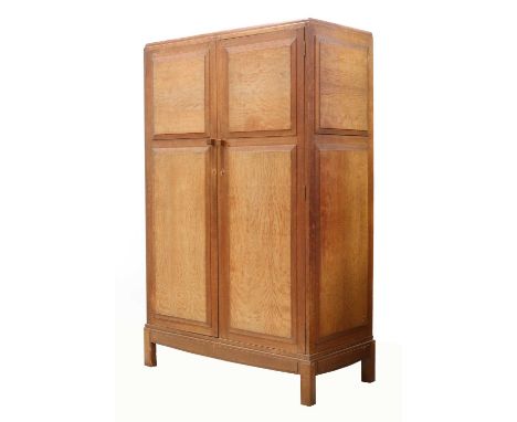 An Arts and Crafts oak wardrobe,by Brynmawr Furniture Makers Ltd., with panelled cupboards and sides, opening to reveal two s