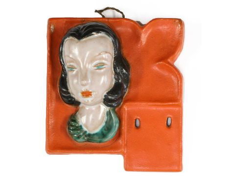 A small Goldscheider pottery wall mask calendar, No. 6880, modelled as a lady with black hair, on an orange mount, with perfo