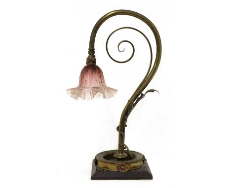 A brass table lamp, in the style of W A S Benson, of scroll form with a cranberry glass shade,51cm high, and another table la