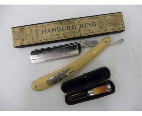 A cased silver mounted cheroot holder and a cut throat razor engraved 'The Hamburg Ring'.