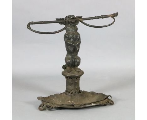 A Victorian cast iron stick stand, modelled as a terrier holding a riding crop, the oval base with foliate dish, stamped with